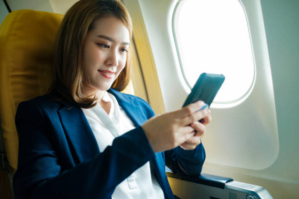 istock Business woman working using phone while sitting in airplane. 1438277873