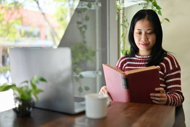 istock Young Asian female college student concentrating on reading a book or textbook 1438277955