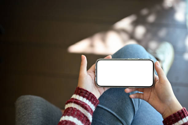 istock A female holding a mobile phone white screen mockup in a horizontal position. 1438278077