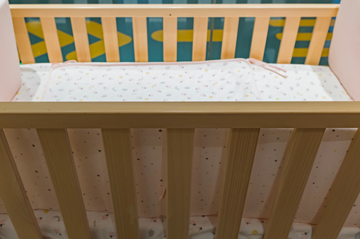 Young baby girl aged 6 to 12 months lying on back in cot playing with her feet.
