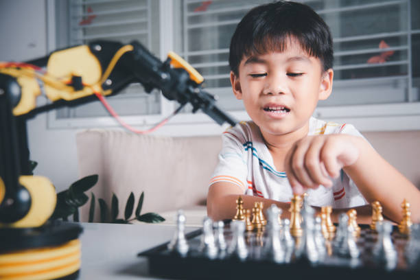 istock Asian little boy is playing chess with robot machine arm 1438280910