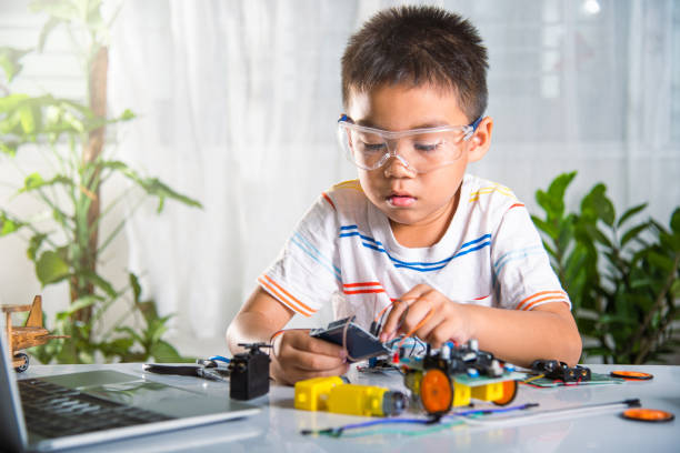 istock Asian kid boy plugging energy and signal cable to sensor chip with open-source hardware and software robot car 1438280942