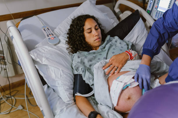 分娩中に病院のベッドにいる妊婦 - midwife human pregnancy women multi ethnic group ストックフォトと画像