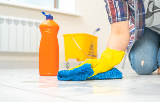 cleaning service. cleaning and care product for laminate and flooring. large orange bottle of laminate floor cleaner. Professional cleaner washing white floor in living room of apartment. cleaning service. Man wearing gloves cleaning floor with microfiber cloth. cleaning and care product for laminate and flooring. large orange bottle of laminate floor cleaner. deep cleaning services stock pictures, royalty-free photos & images