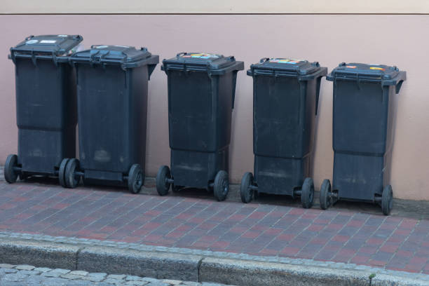 istock Black garbage cans standing in a row on a steeply sloping sidewalk 1438288464