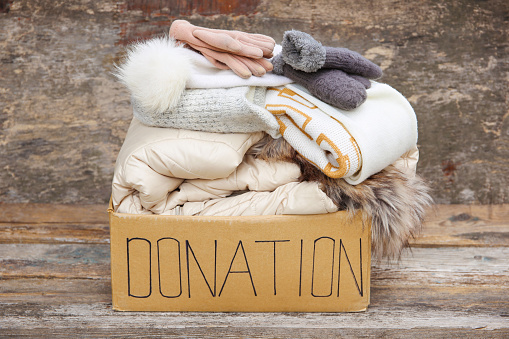 Donation box with winter clothes on an old wooden background.