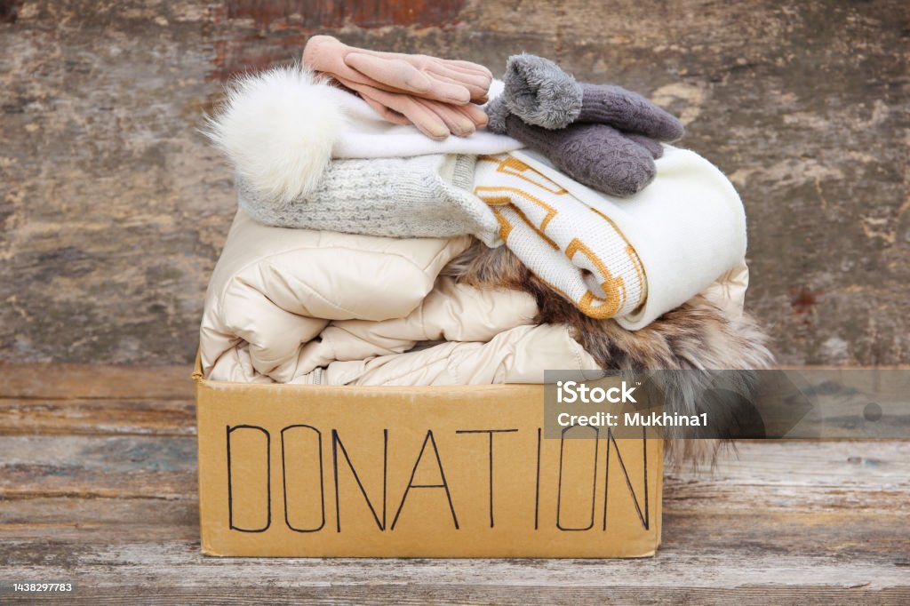 Donation box with winter clothes on an old wooden background. Glove Stock Photo
