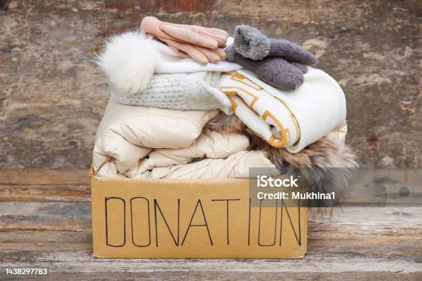 Donation Box With Winter Clothes On An Old Wooden Background Stock Photo - Download Image Now