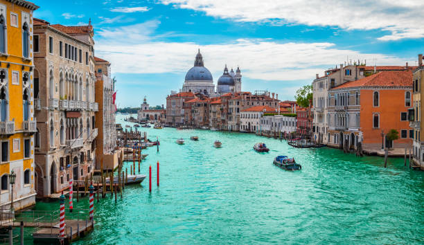 Venice Italy Grand Canal on summer day. Bright and colorful image of Grand Canal (Canal Grande) with small boats on the water. Beautiful old buildings along the waterfront. Dome of Basilica in the background. Travel and tourism in Venice, Italy, Europe. venice italy stock pictures, royalty-free photos & images