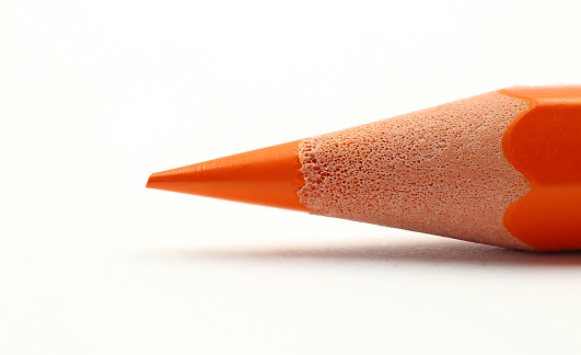 An orange pencil tip photographed with high magnification, on white background