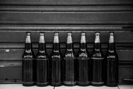 A grayscale shot of empty ember bottles with paint on the neck
