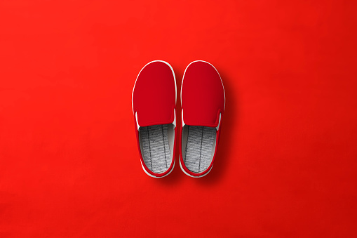 Overhead shot of red slip-on shoes on red background with copy space.