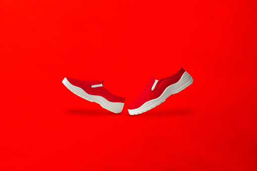 Side view of red slip-on shoes on red background with copy space.