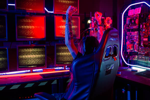 Happy Gamer young plays online video games computer she raises hands to wins tournament stock photo