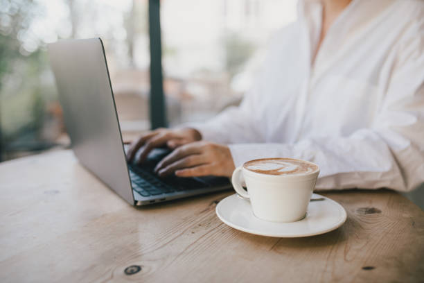 istock Young woman drinking coffee working online using her laptop. 1438305387
