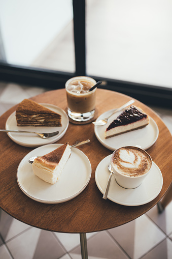 Desserts and coffee on wooden table. Cheesecakes and cappuccino and ice latte.