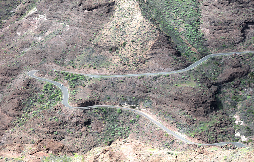 Curved winding road with a white cars in the mountains in Gran Canaria, Spain