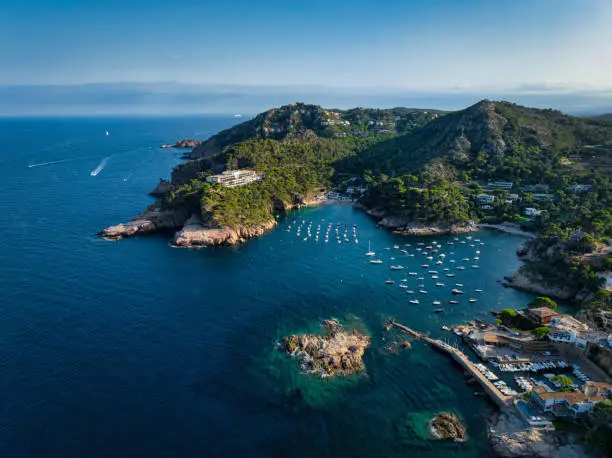 Costa Brava Fornells Coastal Fishing Village Harbor and Beach Drone Panorama over the Mediterranean Sea with anchored Motorboats and Sailboats. Stiched Panorama. Fornells, Begur, Costa Brava, Gerona Province, Catalonia, Spain, Southern Europe.