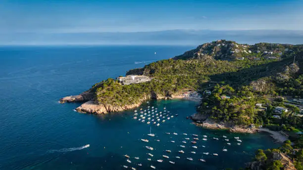 Costa Brava Fornells Coastal Fishing Village Harbor and Beach Drone Panorama over the Mediterranean Sea with anchored Motorboats and Sailboats. Stiched Panorama. Fornells, Begur, Costa Brava, Gerona Province, Catalonia, Spain, Southern Europe.