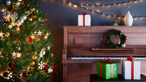 An old piano and a Christmas tree against a dark blue wall background