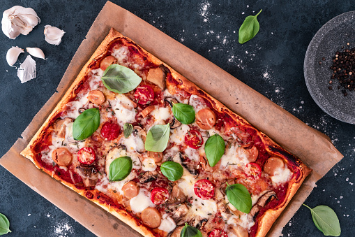 A top view of a rectangular pizza with tomatoes and basil