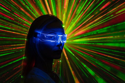 The woman in modern goggles on a laser rays backrground