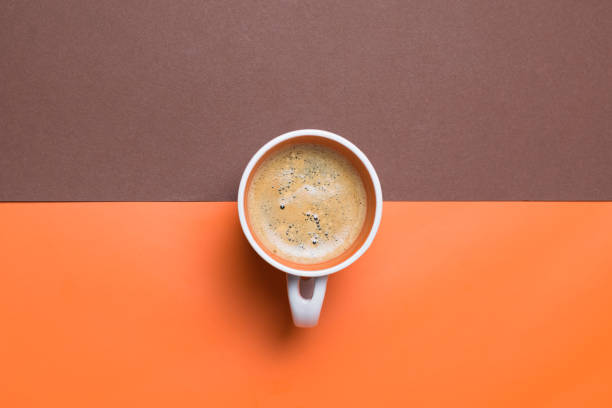 istock Top view of a fresh espresso cup on orange and brown split background 1438314019