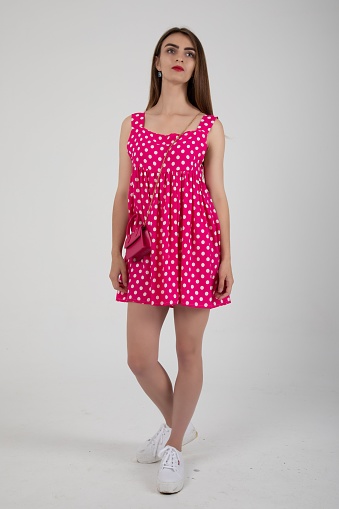 A stunning model posing in a pink polka dot mini dress