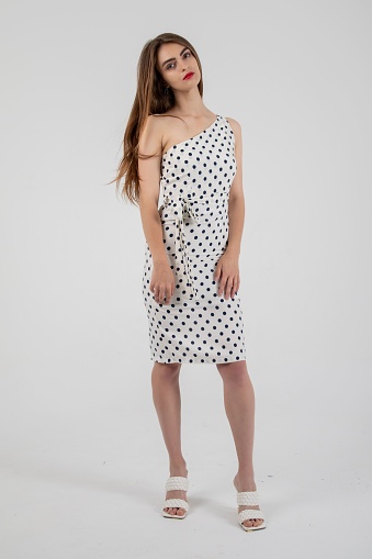 A stunning model posing in a white polka dot dress