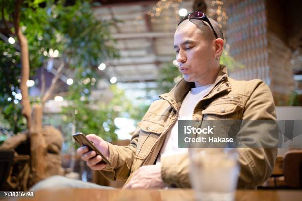 カフェでスマートフォンを見ている男性