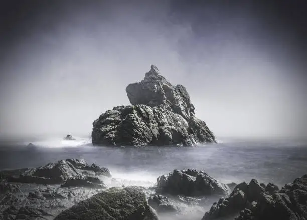 Sea ​​water crashing against rocks on a gray and totally foggy day. 
All this making a dream image.