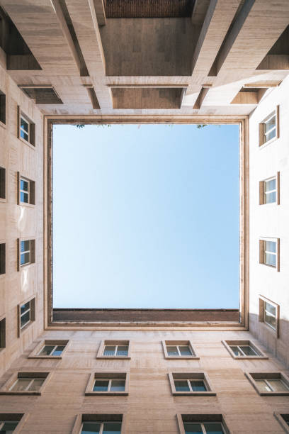 istock Vertical low angle shot of a square with the sky formed by buildings 1438319617