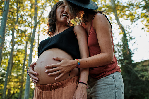 A closeup of a pregnant lesbian couple doing a photoshoot in a park