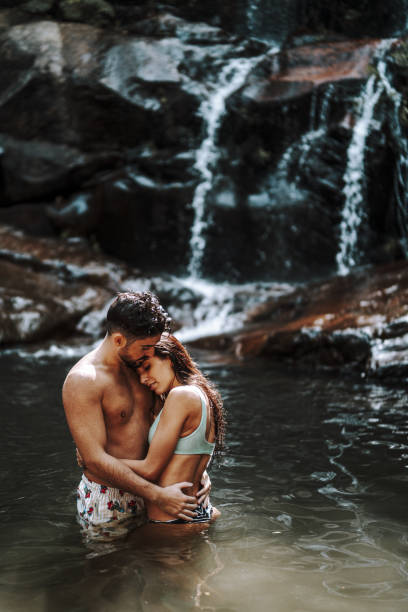 istock Cute young couple in a waterfall pool 1438320774