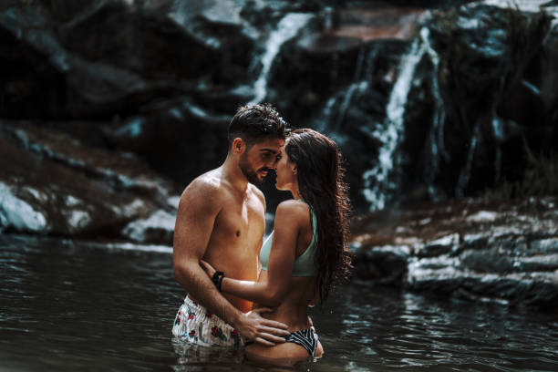 istock Cute young couple in a waterfall pool 1438320785