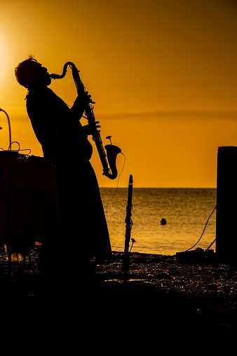 Pesaro, Italy – July 05, 2022: A vertical silhouette shot of a saxophonist at a beach during a sunset