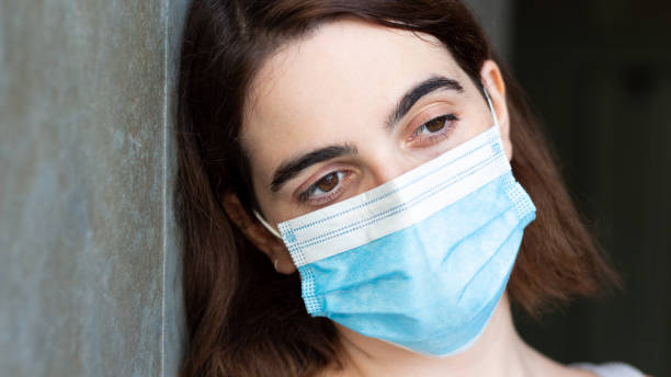 istock Thoughtful female with a facemask leaning on the wall - COVID-19 1438321126