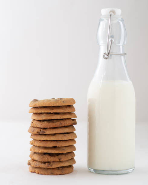 Vertical shot of a stack chocolate chip cookies beside a bottle of milk