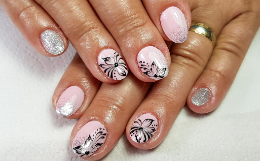 A closeup of a simple manicure with a floral design on almond-shaped nails