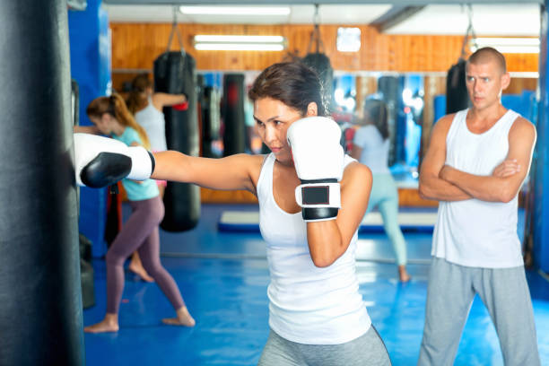 istock Asian woman in boxing gloves practicing punches on punching bag 1438323650