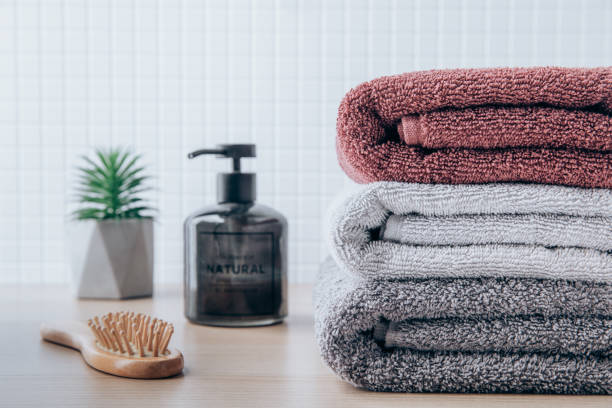istock Towels. Clean fresh fluffy towels and bath accessories on table in bathroom 1438323836