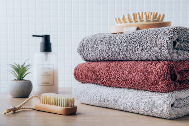 istock Towels. Clean fresh fluffy towels and bath accessories on table in bathroom 1438324007