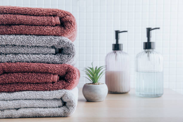 istock Towels. Clean fresh fluffy towels and bath accessories on table in bathroom 1438324100