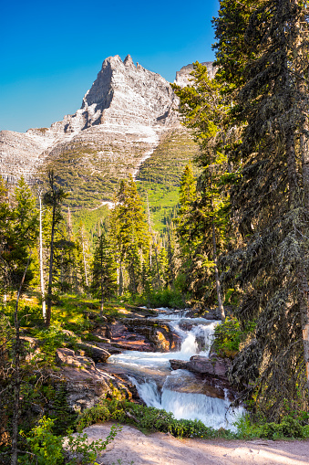 A waterfall along the Saint Mary River at Glacier National Park in Montana during a summer day with clear skies.
