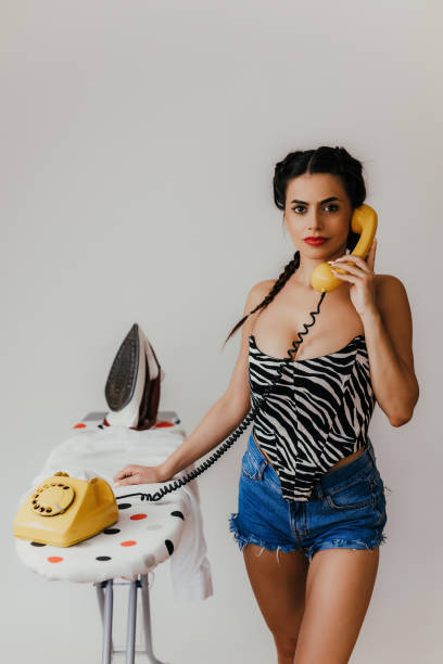 istock Young woman using a landline phone and ironing clothes 1438329412