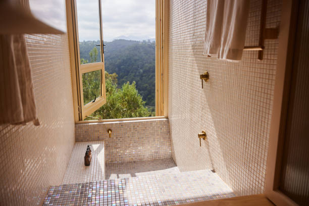 Tiled shower stall with a large open window looking out at a scenic view in the bathroom of a holiday home