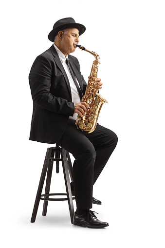 Mature male sax player playing and sitting on a chair isolated on white background