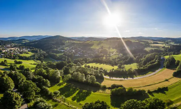 Aerial view with drone of the village Grueb near town Grafenau in Bavarian Forest with mountains and landscape in summer with sun and sunrays, Germany