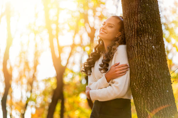 istock Beautiful woman leaning on a tree and enjoying in autumn 1438330955