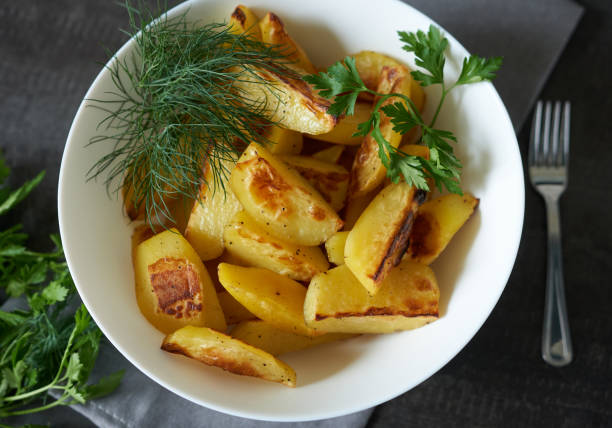 istock Baked potatoes in a white plate with herbs, close-up. 1438332011